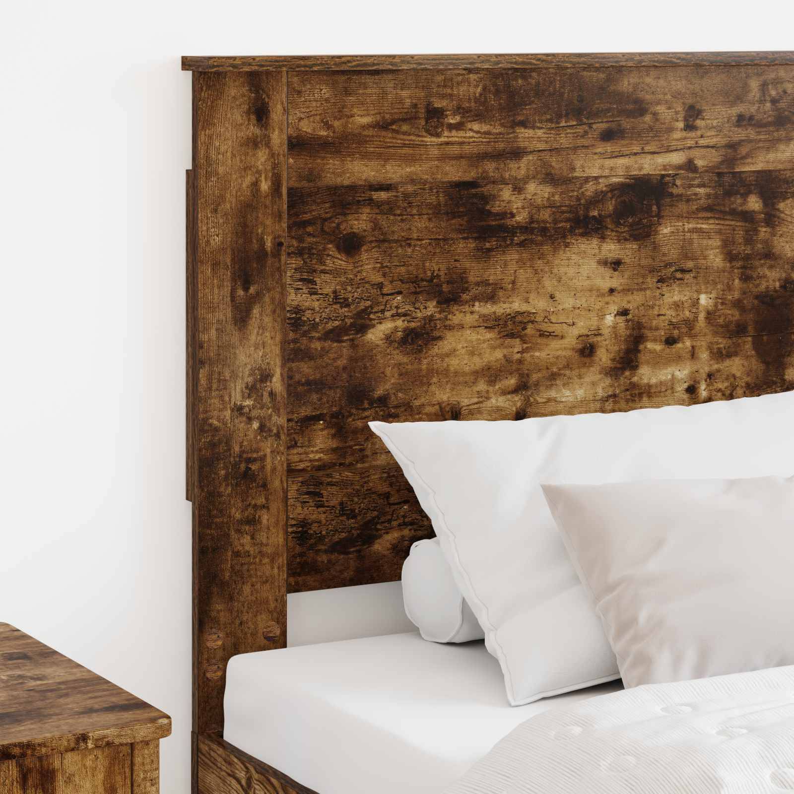 Ein Holzbett mit rustikalem Kopfteil, weißen Kissen und einer weißen Matratze in einer minimalistischen Schlafzimmereinrichtung.