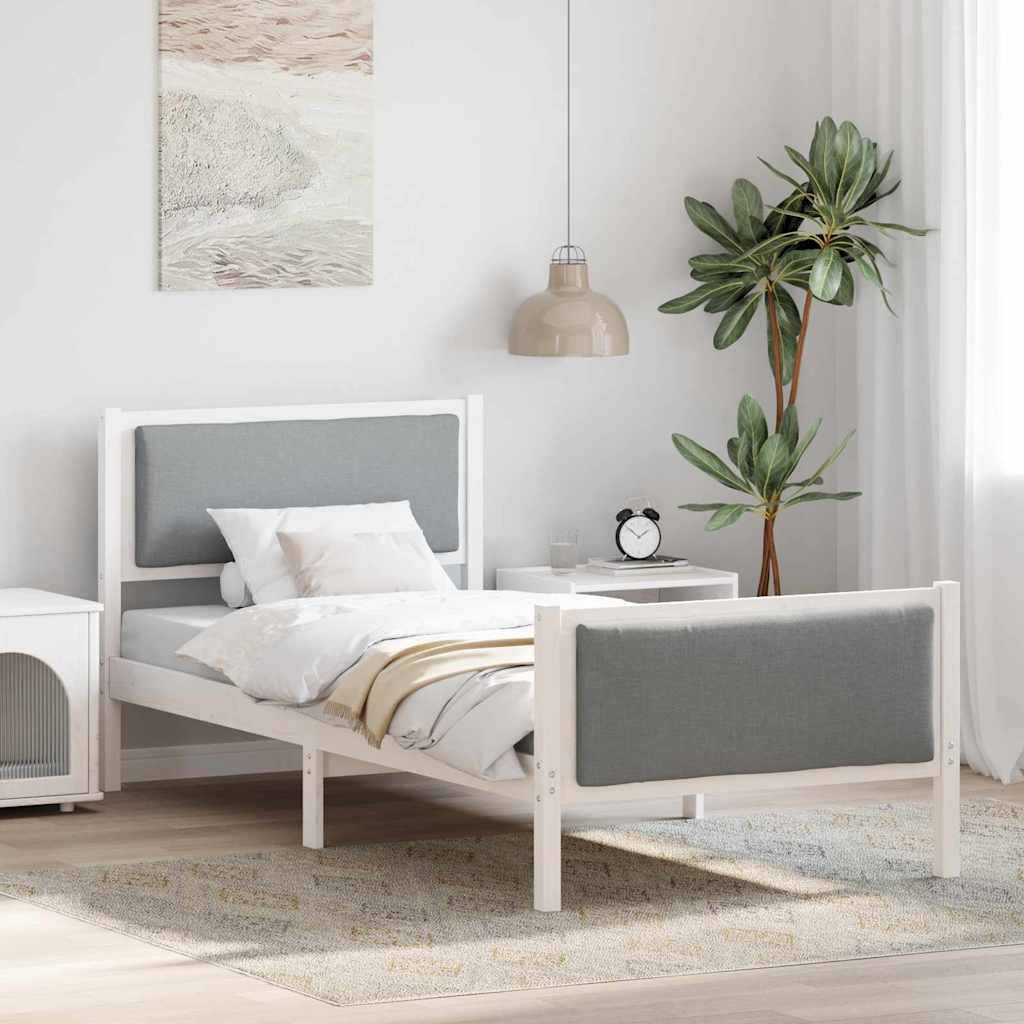 Ein modernes Schlafzimmer mit einem Einzelbett, das einen grauen gepolsterten Kopf- und Fußteil aufweist, ein Nachttisch mit einer Lampe und einer Zimmerpflanze.
