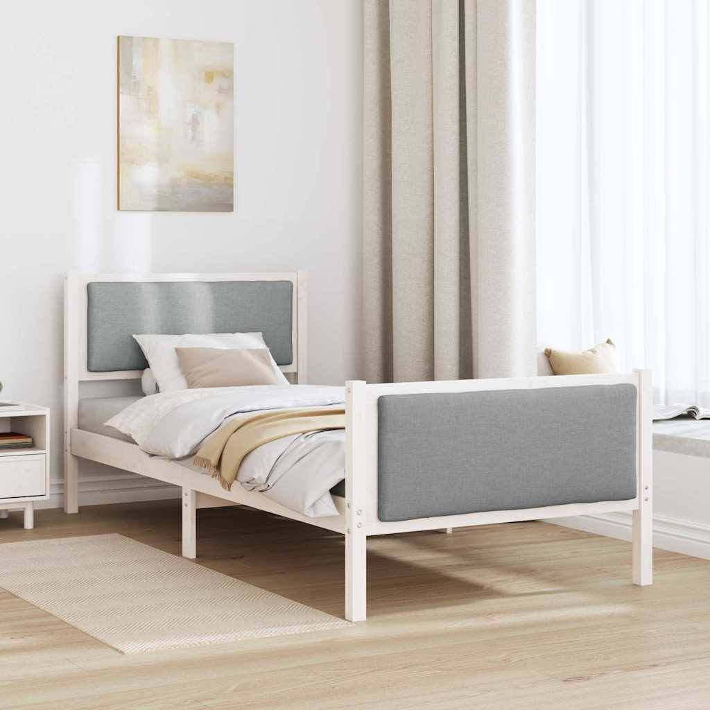 Ein ordentlich gemachtes Bett mit einem grauen gepolsterten Kopf- und Fußteil steht vor einer hellen Wand. Auf der linken Seite befindet sich ein Nachttisch mit einer Schublade.