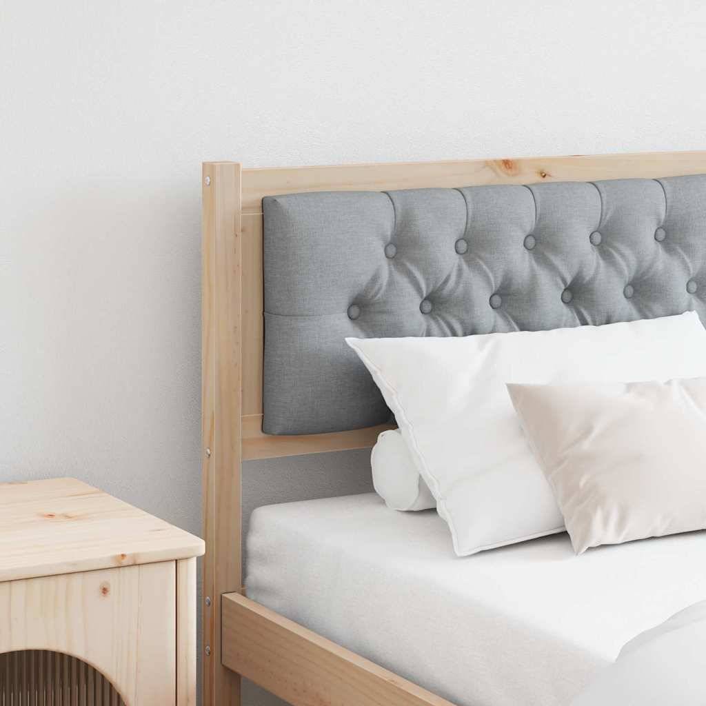 Ein ordentlich gemachtes Bett mit einem grauen gesteppten Kopfteil, weißer Bettwäsche und zwei Kissen. Ein kleiner hölzerner Nachttisch steht neben dem Bett.