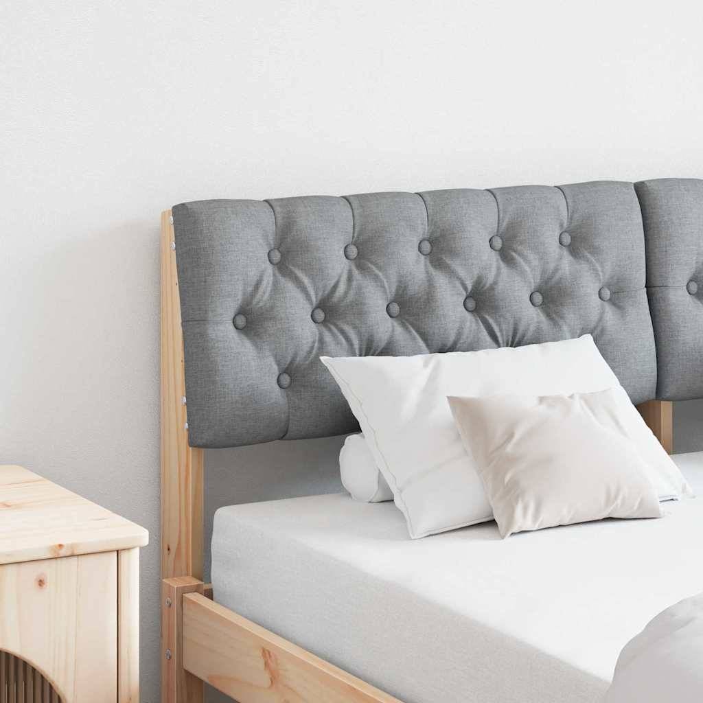 Ein modernes Schlafzimmerinterieur mit einem hellholzernen Bett, das ein grau gestepptes Kopfteil, weiße Bettwäsche und dekorative Kissen aufweist.