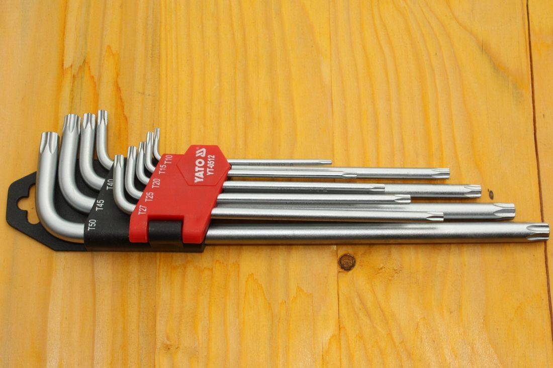 Ein Satz von L-förmigen Sechskantschlüsseln, nach Größe organisiert, von 0,7 bis 5, jeder mit Maßangaben in Millimetern gekennzeichnet, auf einer Holzoberfläche angezeigt.