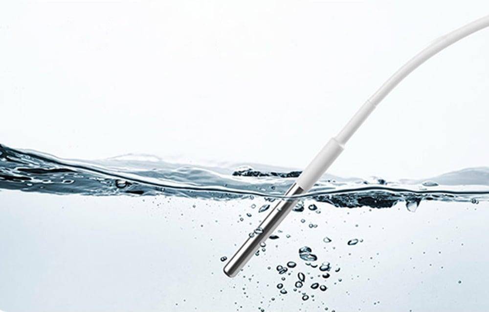 Eine weiße Sonde ist teilweise in klarem Wasser eingetaucht, mit Blasen um sie herum, was darauf hindeutet, dass sie möglicherweise die Wasserqualität testet oder misst.