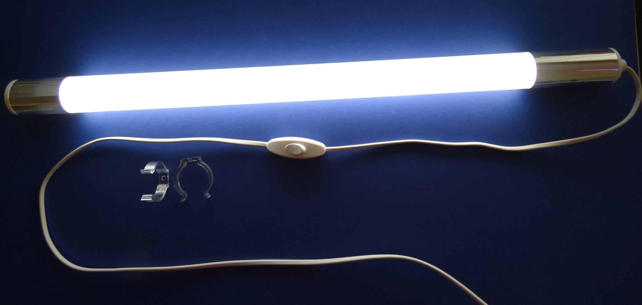 Ein weißer LED-Lichtstreifen mit einem Schalter und einer Montageklammer auf einer dunkelblauer Oberfläche, wobei ein Teil des Netzkabels sichtbar ist.