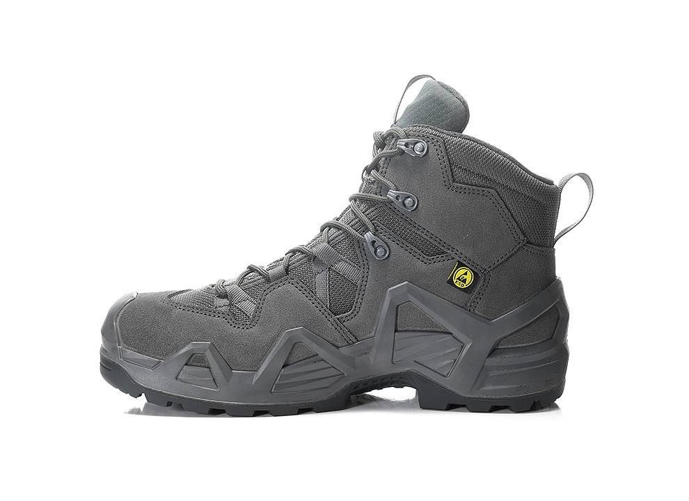 Grauer Wanderschuh mit robuster Sohle, Knöchelschutz und gelbem Sicherheitsemblem an der Seite; entwickelt für Outdoor-Aktivitäten und raues Gelände.