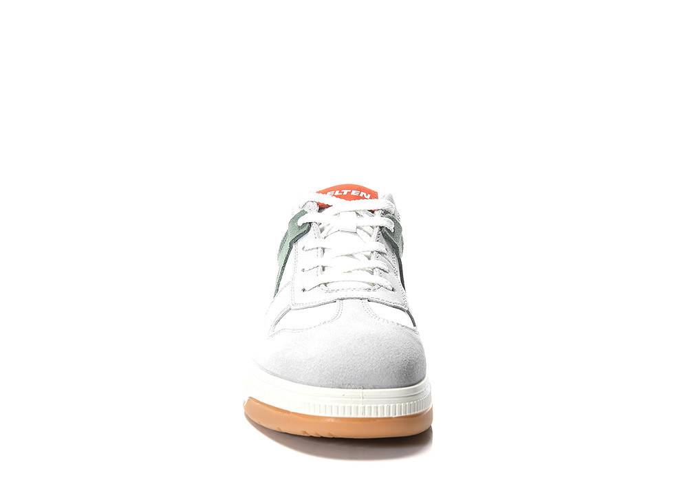 Ein weißer Sneaker mit grünen Akzenten und einer hellbraunen Sohle, von vorne betrachtet. Der Sneaker hat weiße Schnürsenkel und ein rotes Etikett auf der Zunge.