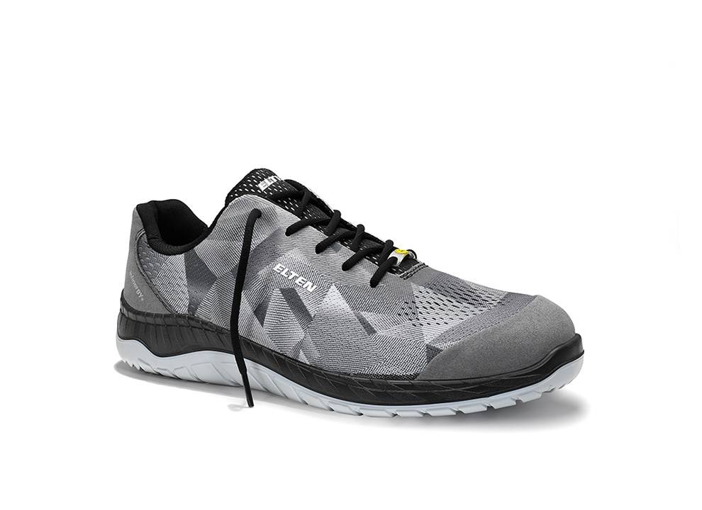 Ein grau-schwarzer Sportschuh mit geometrischem Muster, weißer strukturierter Sohle und schwarzen Schnürsenkeln, präsentiert auf einem schlichten Hintergrund.