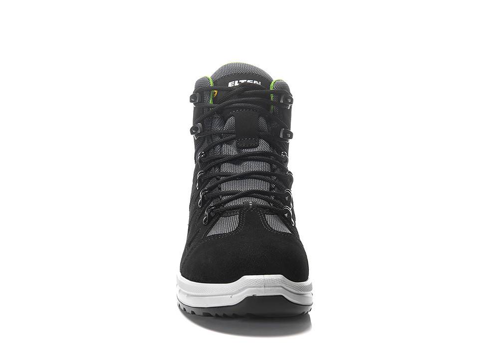 Ein schwarzer und grauer Wanderschuh mit einer robusten Sohle, schwarzen Schnürsenkeln und grünen Akzenten, von vorne gegen einen einfarbigen weißen Hintergrund betrachtet.