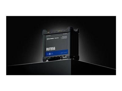 Ein schwarzes und blaues RUT956-Gerät von Teltonika Networks, das auf einer dunklen Oberfläche vor einem schwarzen Hintergrund platziert ist und sein kompaktes Design präsentiert.