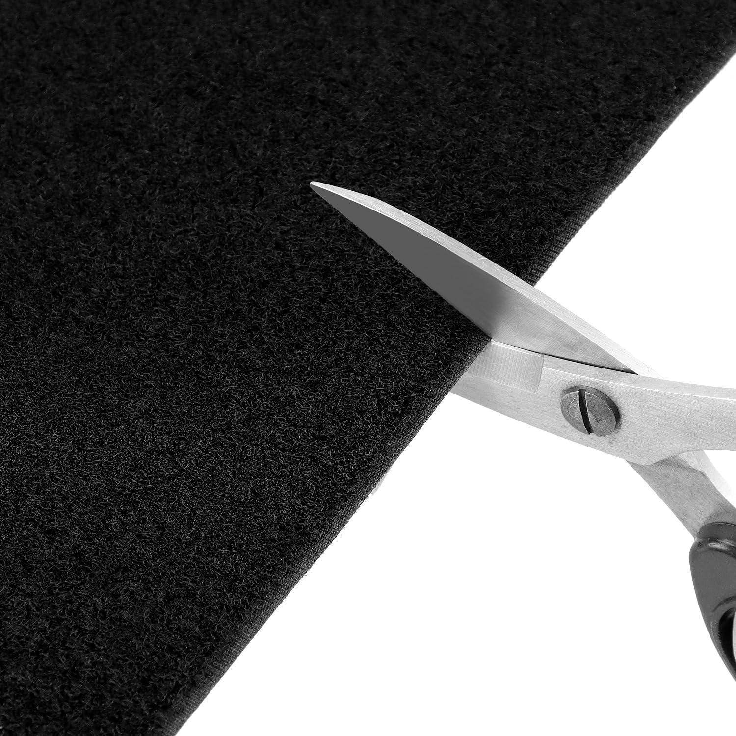 Schere, die schwarzen Stoff diagonal durchschneidet, mit Fokus auf der scharfen Klinge und dem strukturierten Material.