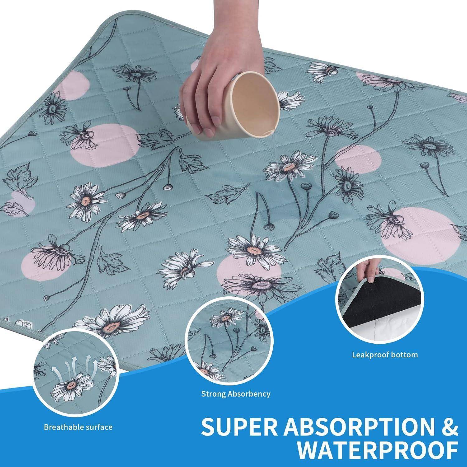 Eine Hand verschüttet Flüssigkeit auf einer Matte mit Blumenmuster, wobei ihre starke Saugfähigkeit und wasserdichten Eigenschaften sowie der auslaufsichere Boden hervorgehoben werden.