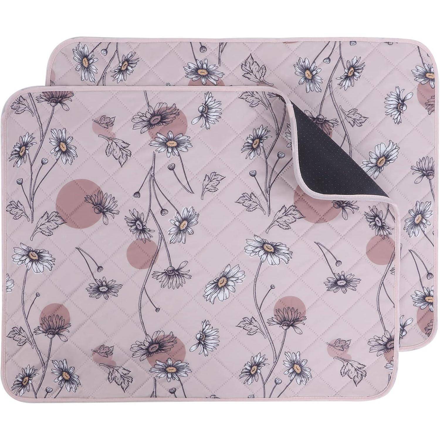 Zwei identische Steppmatten mit rosa Hintergrund zeigen ein Muster aus weißen Gänseblümchen und abstrakten Kreisen, wobei eine Matte die andere leicht überlappt.