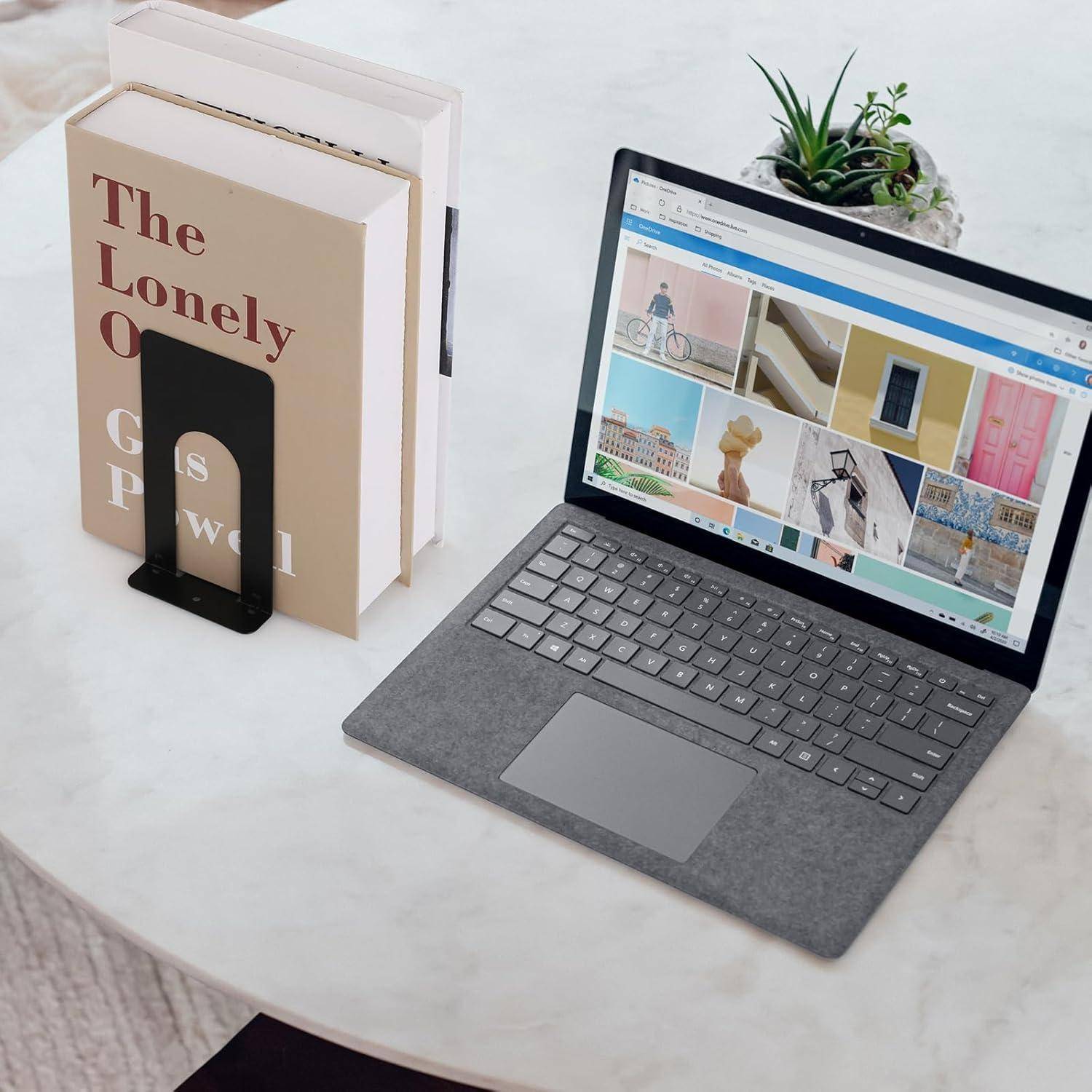 Ein Laptop auf einem runden Tisch zeigt einen Webbrowser mit Bildern. Daneben steht ein Buch mit dem Titel 