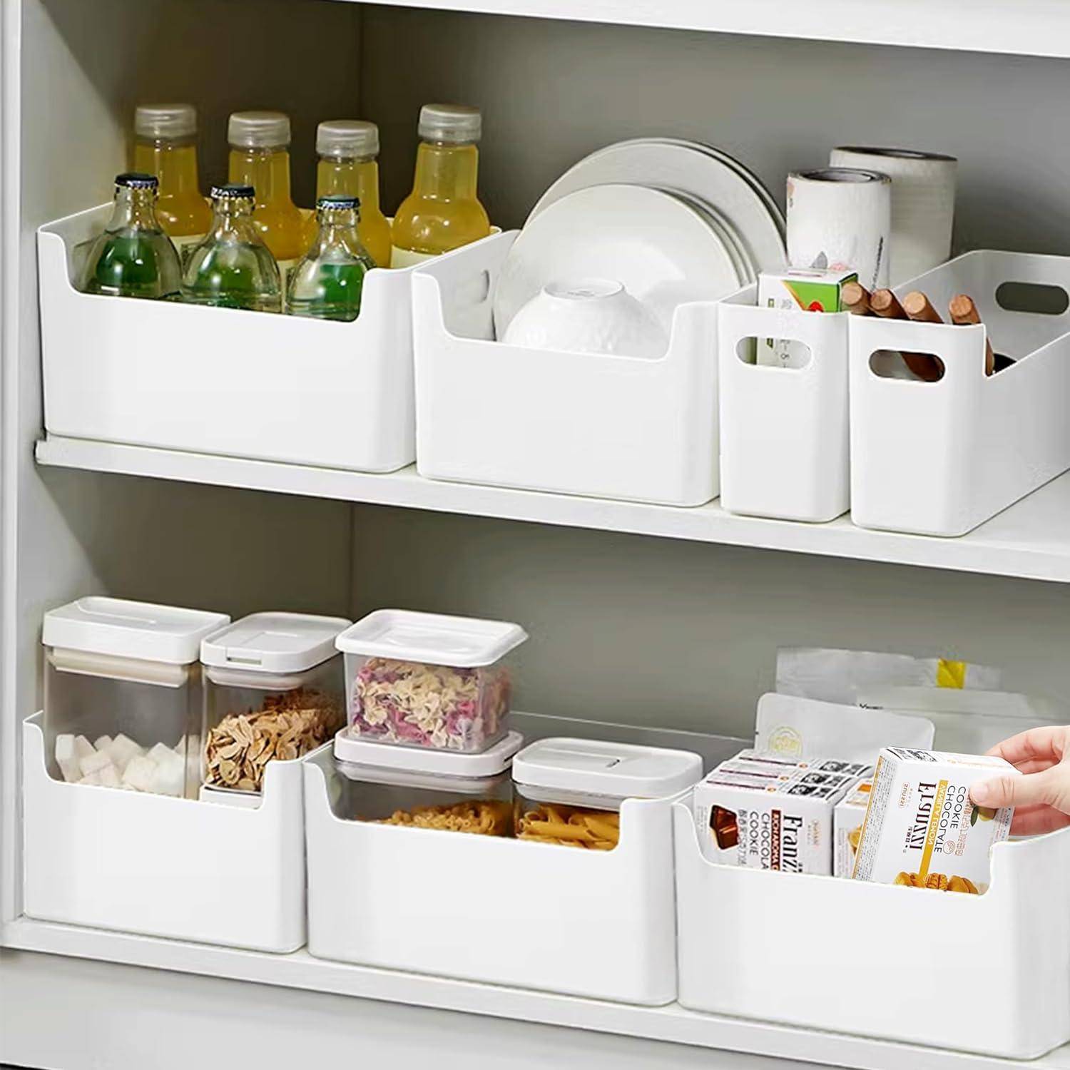 Küchenschrank organisiert mit weißen Behältern; oberes Regal enthält Getränke, Geschirr und Küchenpapier; unteres Regal beherbergt Lebensmittelbehälter und Snacks.