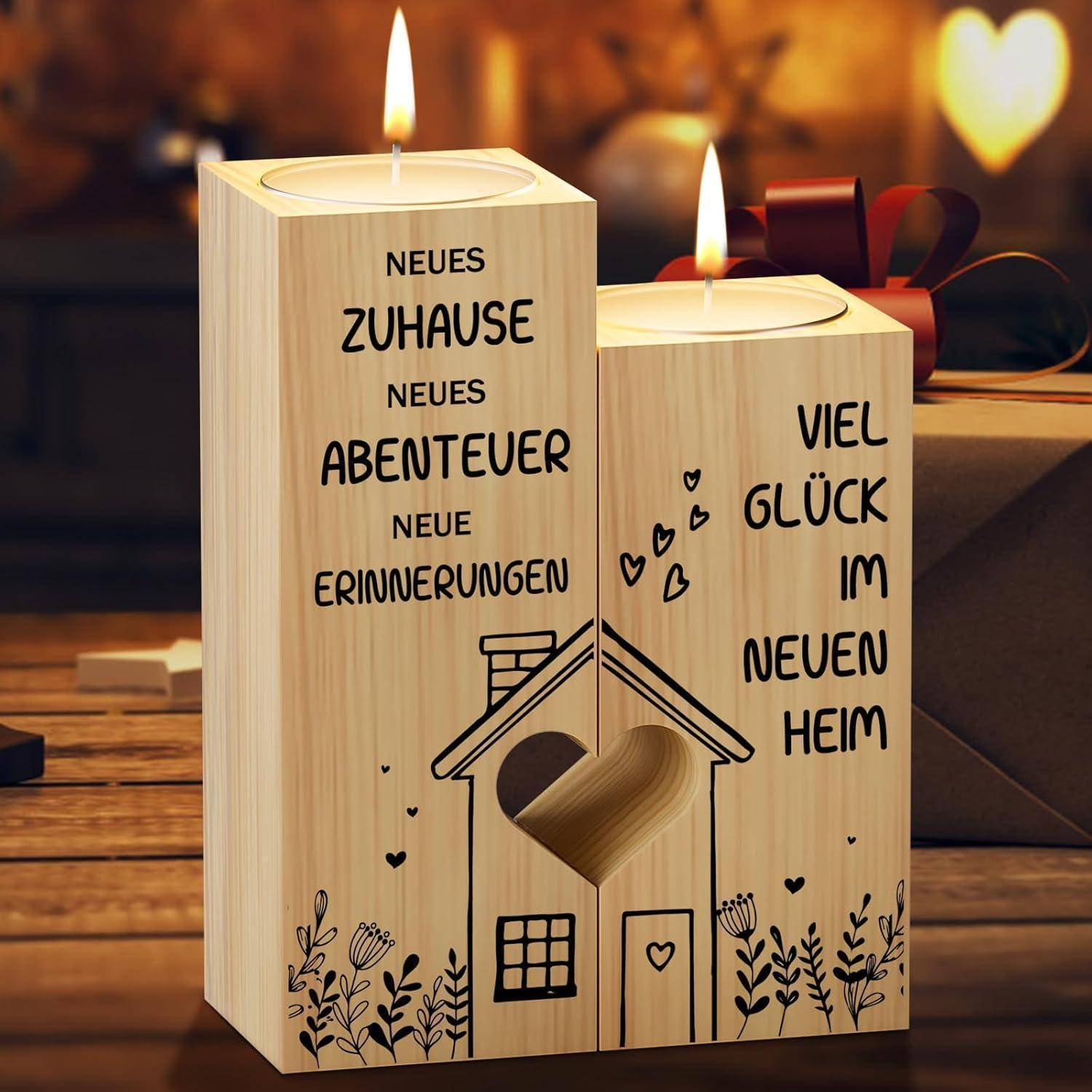 Zwei Holzkerzenhalter mit gravierten deutschen Texten. Der linke liest sich 'Neues Zuhause, neue Abenteuer, neue Erinnerungen' und der rechte liest 'Viel Glück im neuen Heim.' Ein Herzdesign und leuchtende Kerzen verleihen Wärme.