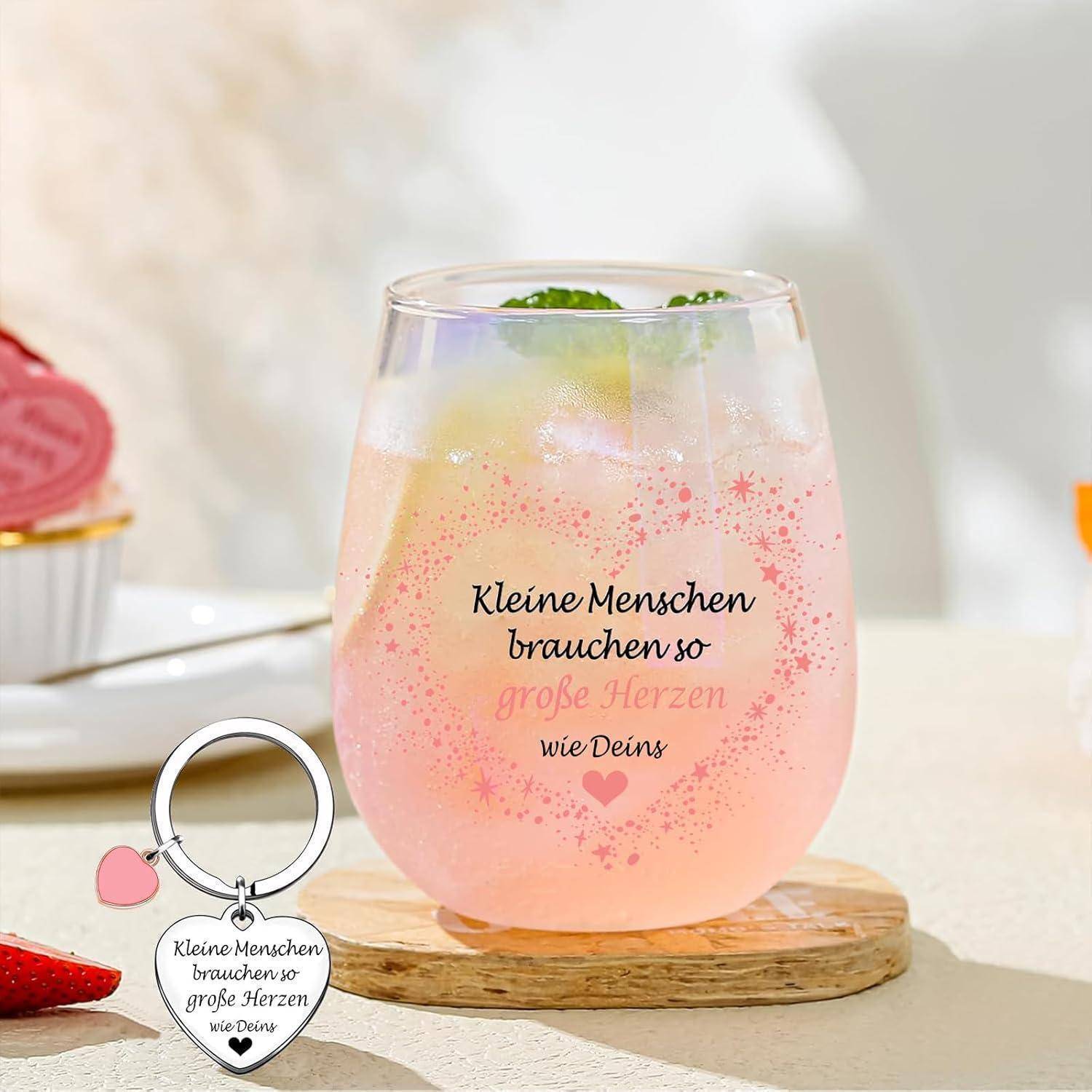 Ein Glas Limonade in rosa mit Limettenscheiben, Text 'Kleine Menschen brauchen so große Herzen'. Schlüsselanhänger in Herzform mit demselben Text.