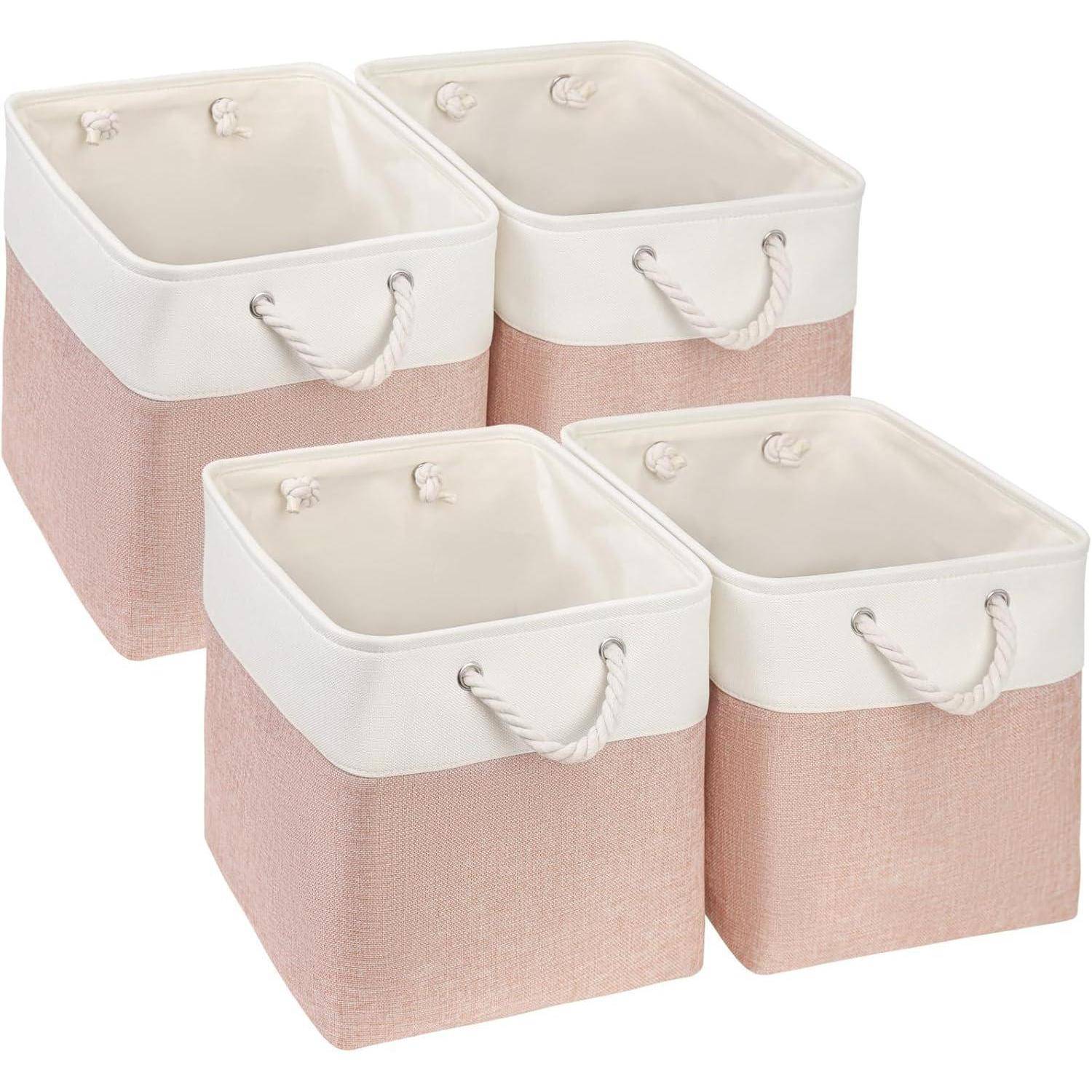 Vier rosa-weiße Aufbewahrungsboxen aus Stoff mit Seilgriffen, die in einer quadratischen Anordnung platziert sind.