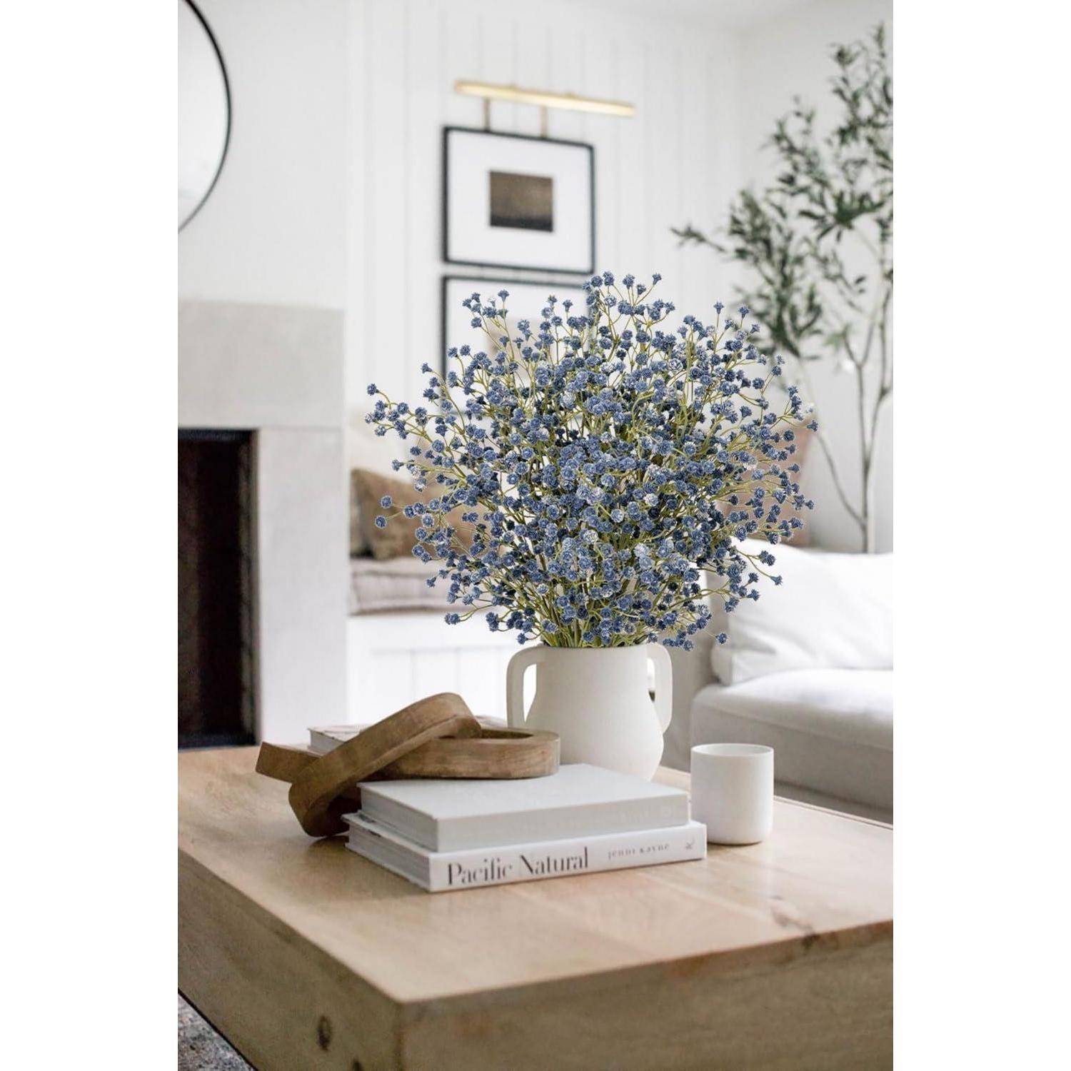 Eine Vase mit lila Blumen auf einem Holzcouchtisch, umgeben von Büchern und einer Sandale, in einem gemütlichen, minimalistischen Wohnzimmer.