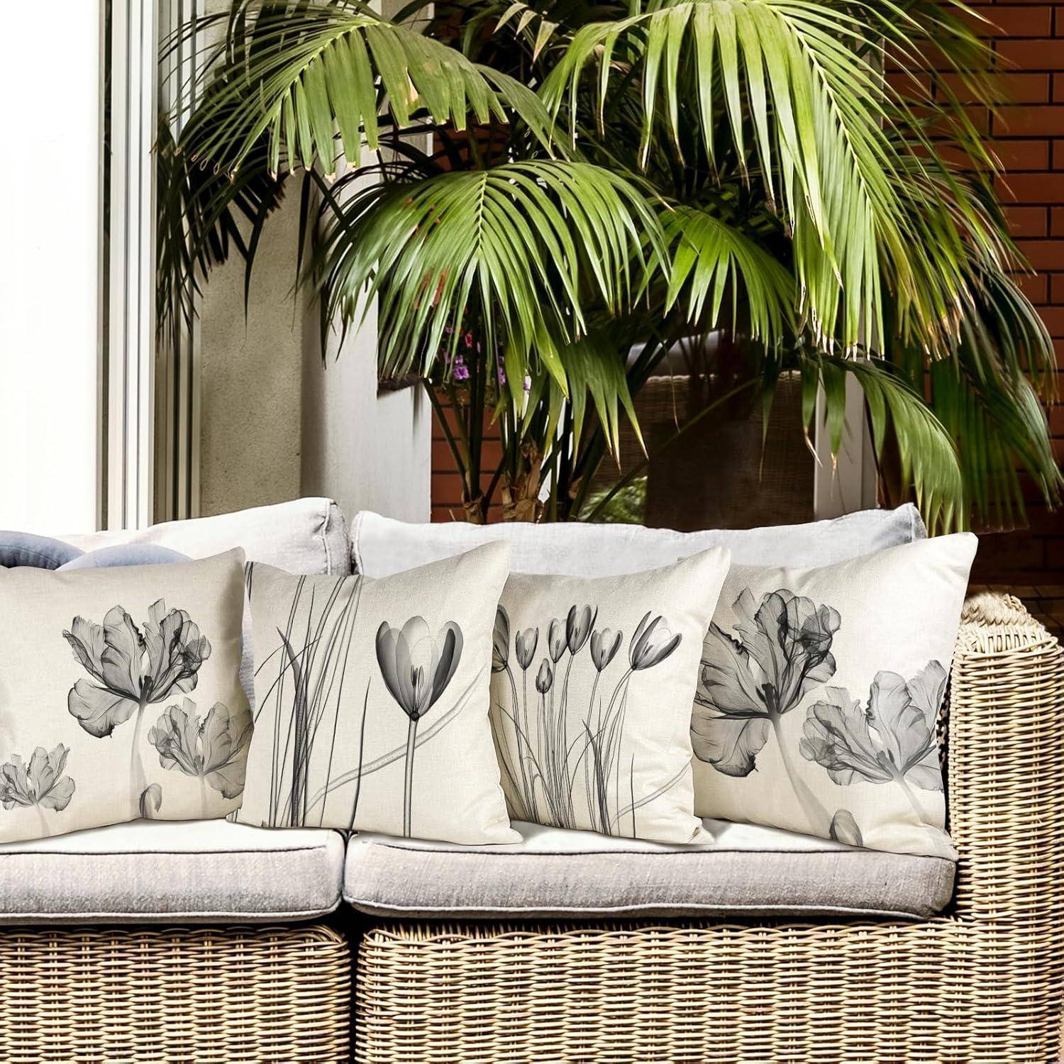 Outdoor-Rattansofa mit blumenmusterverzierten Kissen, umgeben von Topfpflanzen und einem großen Fenster, das eine gemütliche Gartenatmosphäre schafft.