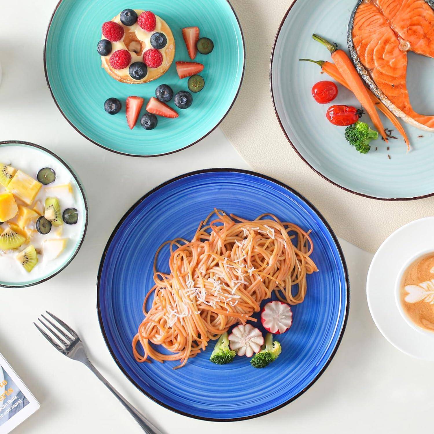 Ein Überkopf-Bild zeigt verschiedene Gerichte: Obsttorten auf blauen Tellern, Lachs und Gemüse, Spaghetti mit Brokkoli und einen Latte mit Latte-Kunst.