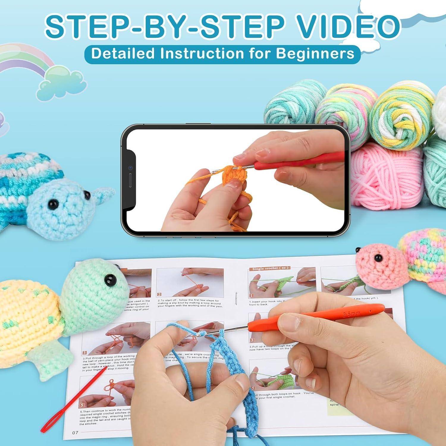 Hände, die orangefarbenes Garn häkeln, auf dem Handybildschirm zu sehen, umgeben von Garnknäueln, Häkelanleitung und Spielzeug-Schildkröten. Text lautet: „Schritt-für-Schritt-Video, detaillierte Anleitung für Anfänger
