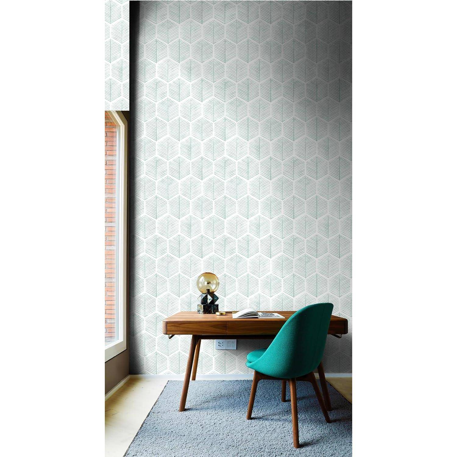Ein moderner Arbeitsbereich mit einem Holzschreibtisch und einem grünen Stuhl, vor einer geometrisch gemusterten Wand. Eine Lampe und ein Buch befinden sich auf dem Schreibtisch.