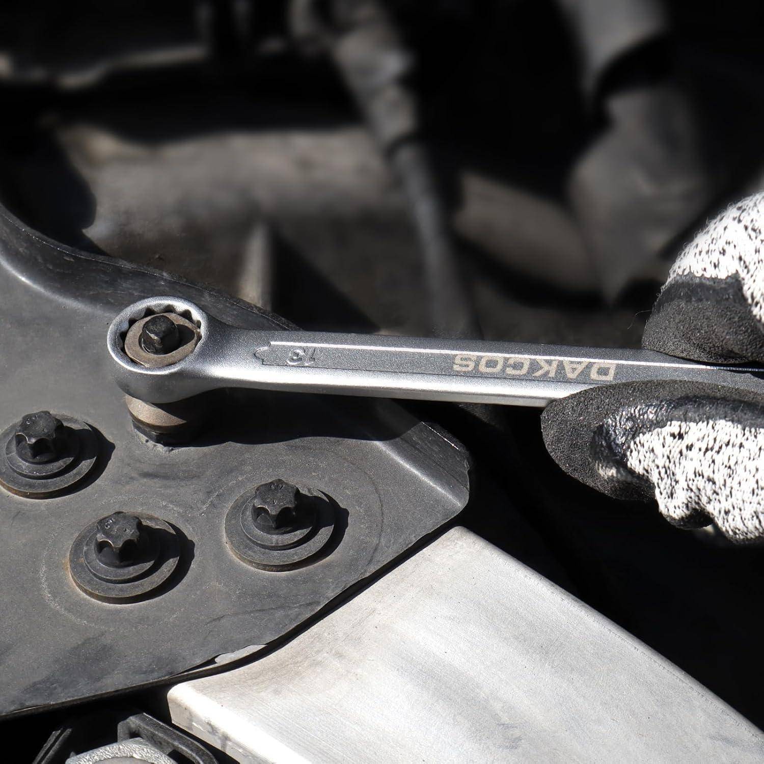 Eine Hand mit Handschuh benutzt einen Schraubenschlüssel, um Schrauben an einem mechanischen Teil, möglicherweise einem Motor, festzuziehen. Der Fokus liegt auf den Werkzeugen und Händen.
