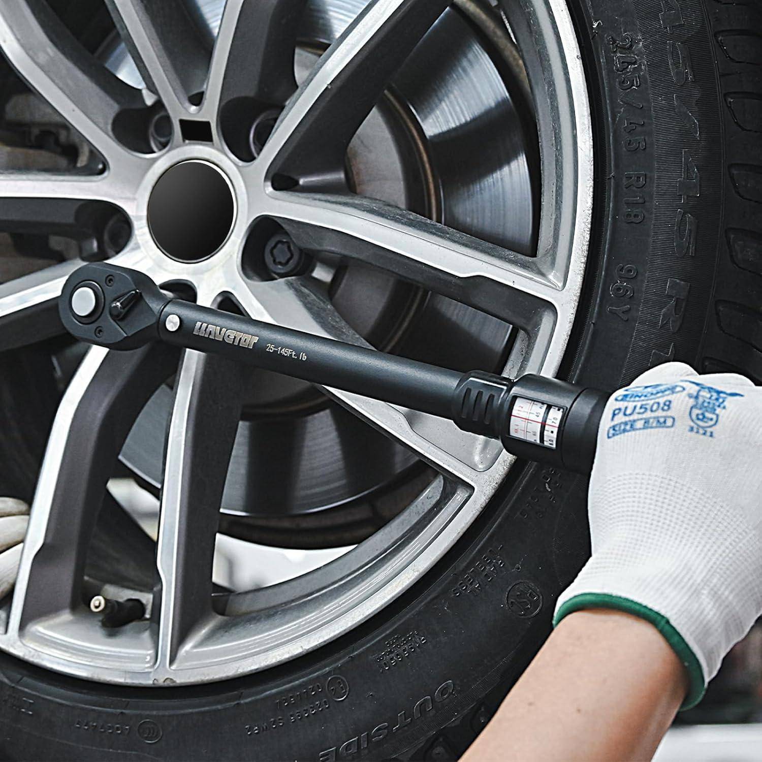 Eine Person, die einen Drehmomentschlüssel benutzt, um eine Radmutter an einem Autoreifen anzuziehen, trägt dabei einen weißen Handschuh, der mit blauem Text für Sicherheitszwecke markiert ist.