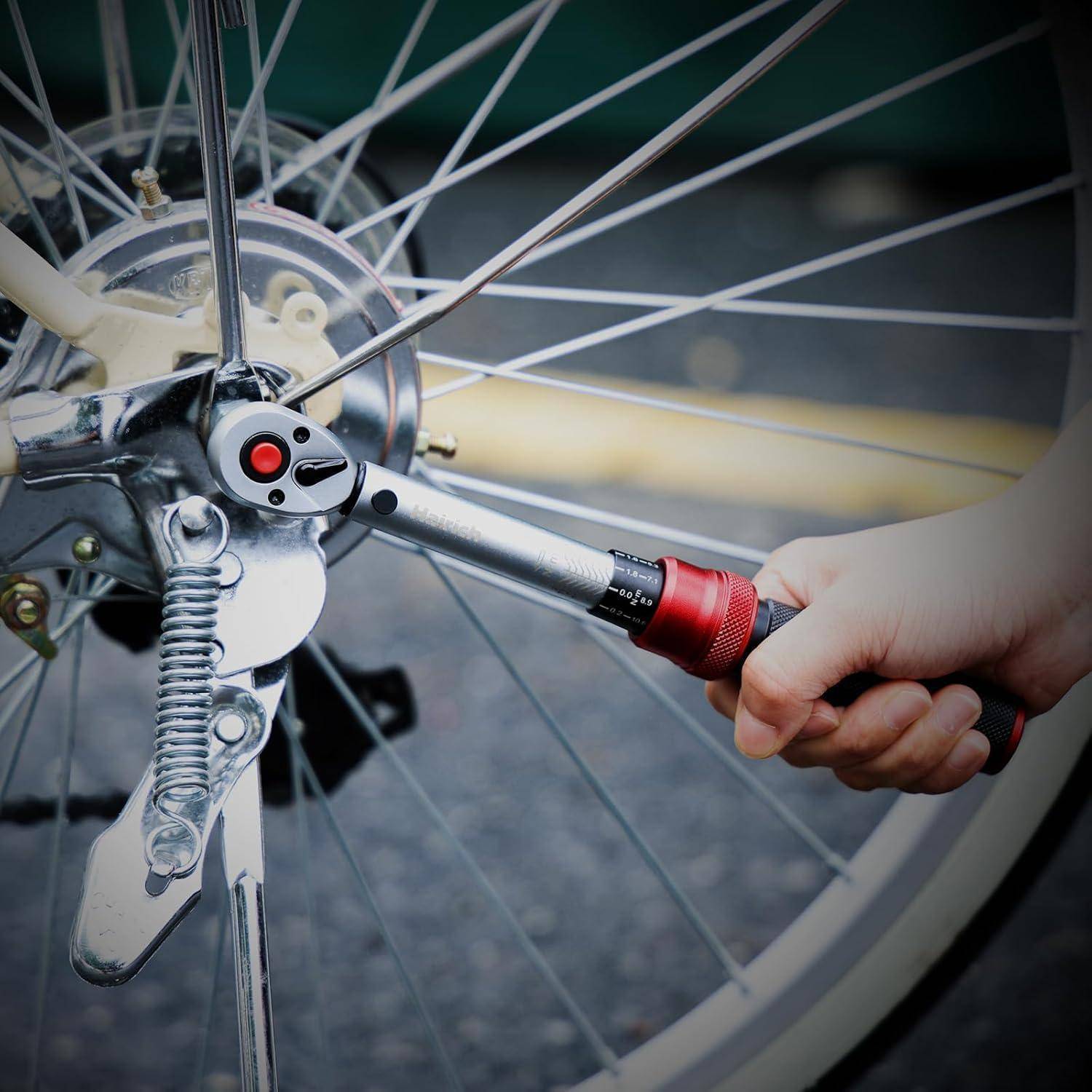 Eine Hand zieht eine Schraube am Fahrradrad mit einem Ratschenschlüssel an, was Wartungs- oder Reparaturarbeiten am Fahrrad andeutet.