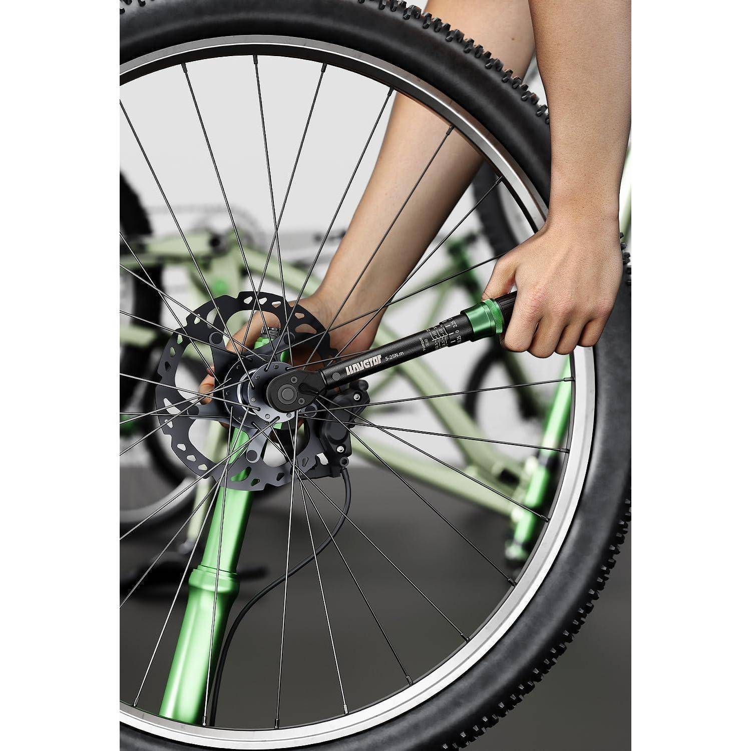 Eine Person justiert das Hinterrad eines grünen Fahrrads und konzentriert sich dabei auf den Bremsscheibenbereich. Das Bild betont Fahrradinstandhaltung.