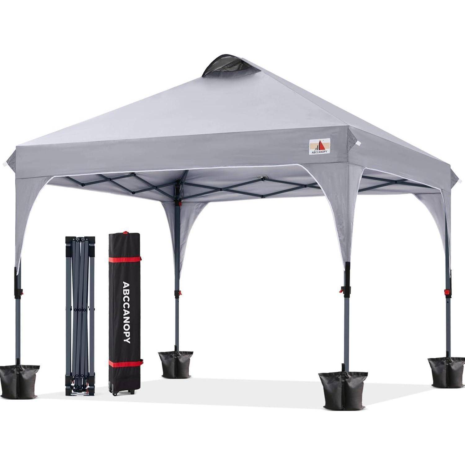 Ein tragbares graues Pavillon-Zelt mit vier Beinen und roten Akzenten, präsentiert mit seiner Tragetasche und Gewichten zur Stabilisierung.