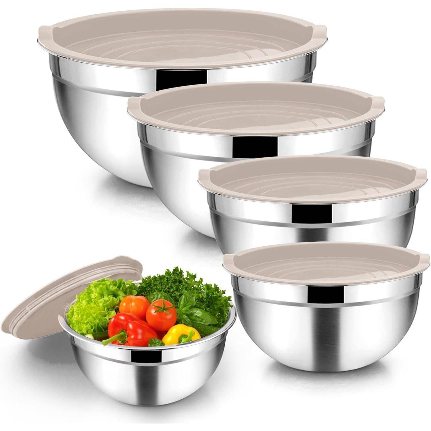 Ein Set aus fünf Edelstahl-Rührschüsseln mit beigen Kunststoffdeckeln. Eine Schüssel ist mit frischem Gemüse gefüllt, darunter Tomaten und Grünblättrige.