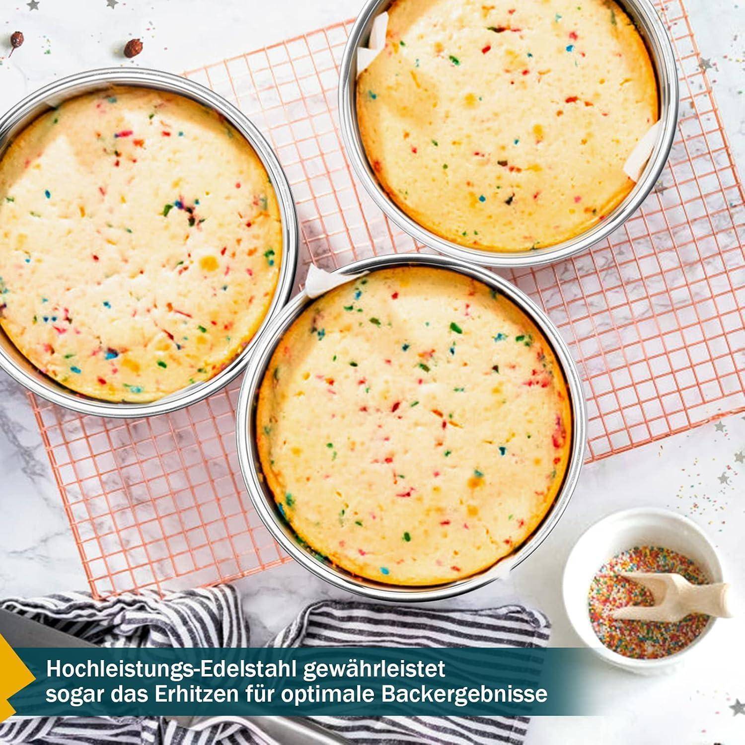 Drei runde Backformen mit gebackenen Konfetti-Kuchenschichten auf einem Kuchengitter, mit einer Schüssel Streusel in der Nähe. Text: 'Hochleistungs-Edelstahl gewährleistet sogar das Erhitzen für optimale Backergebnisse'.