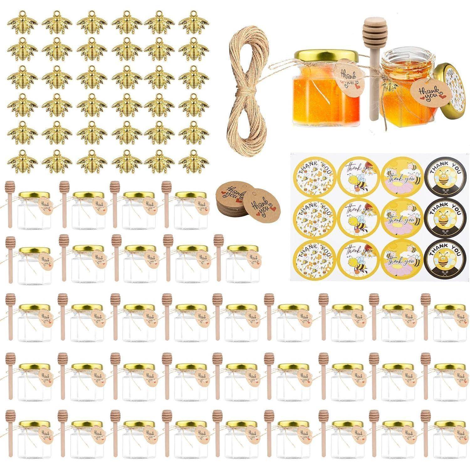 Ein Set, das Glasgläser mit Honig, Honiglöffel, Bienen-Sticker und dekorative Bienen enthält, wahrscheinlich zum Basteln oder als Geschenk.