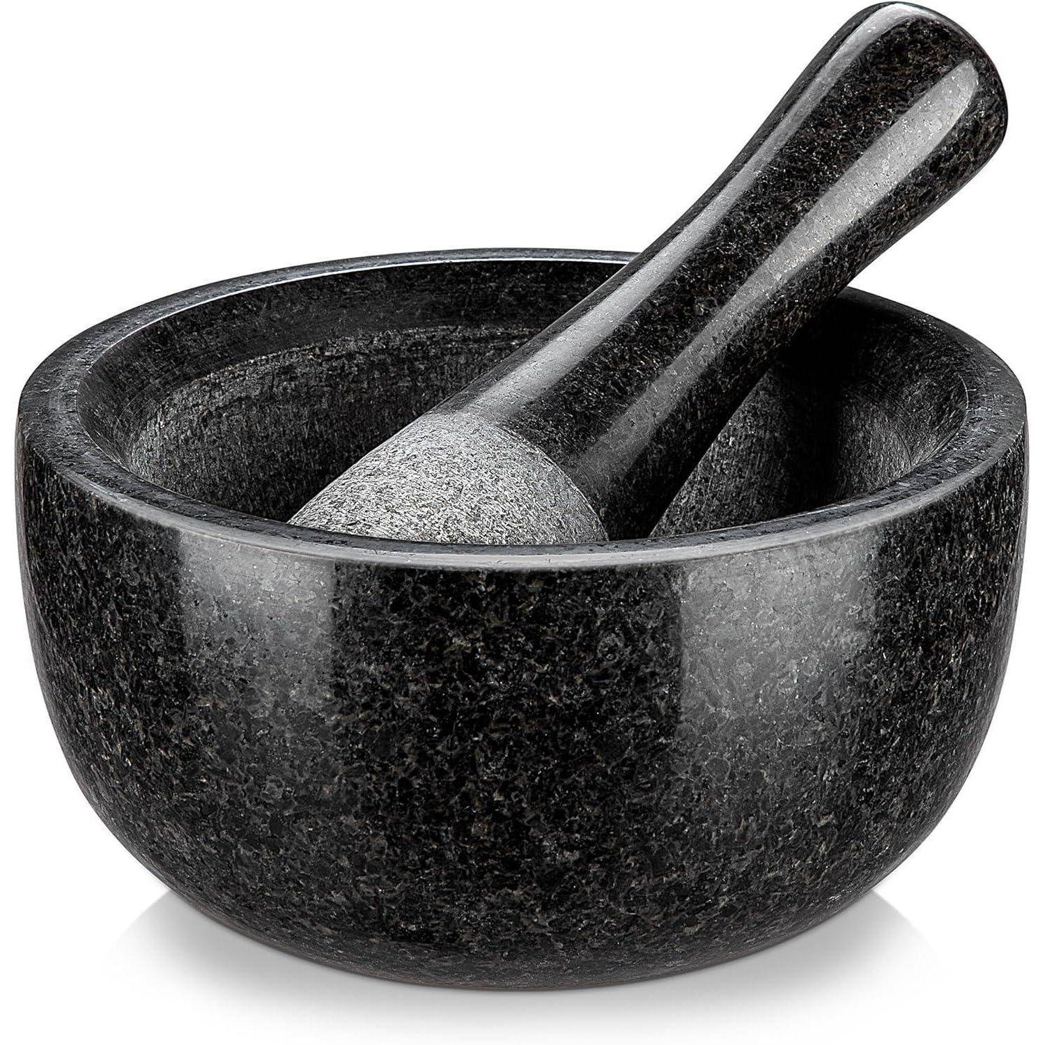Ein schwarzes Mörser- und Pistillset mit polierter Oberfläche, das zum Mahlen und Zermahlen von Zutaten beim Kochen oder bei der Herstellung von Kräuterpräparaten verwendet wird.