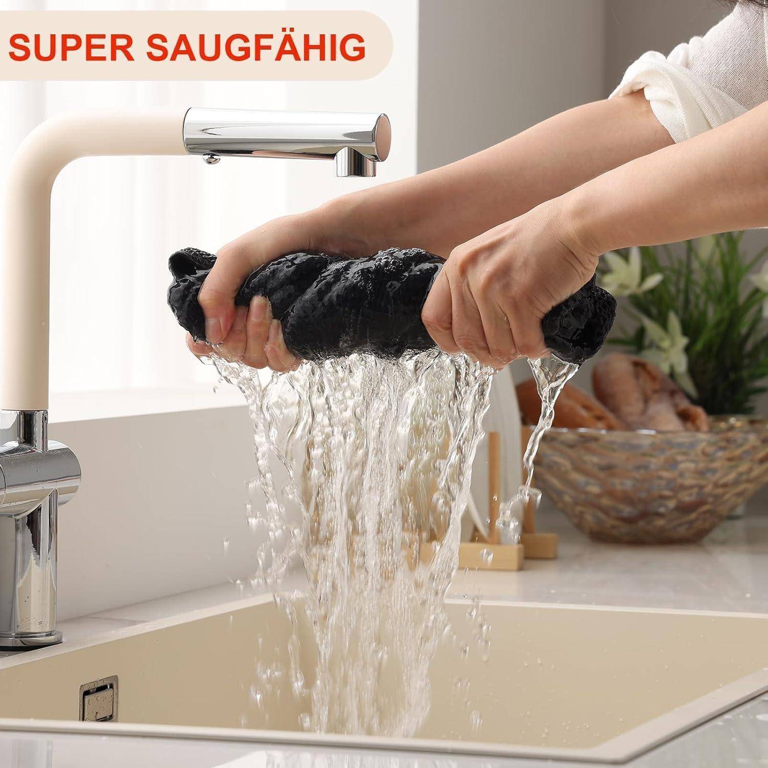 Hände, die ein schwarzes Tuch unter einem Küchenhahn auswringen, wobei Wasser aus dem Tuch läuft. Der Text lautet 