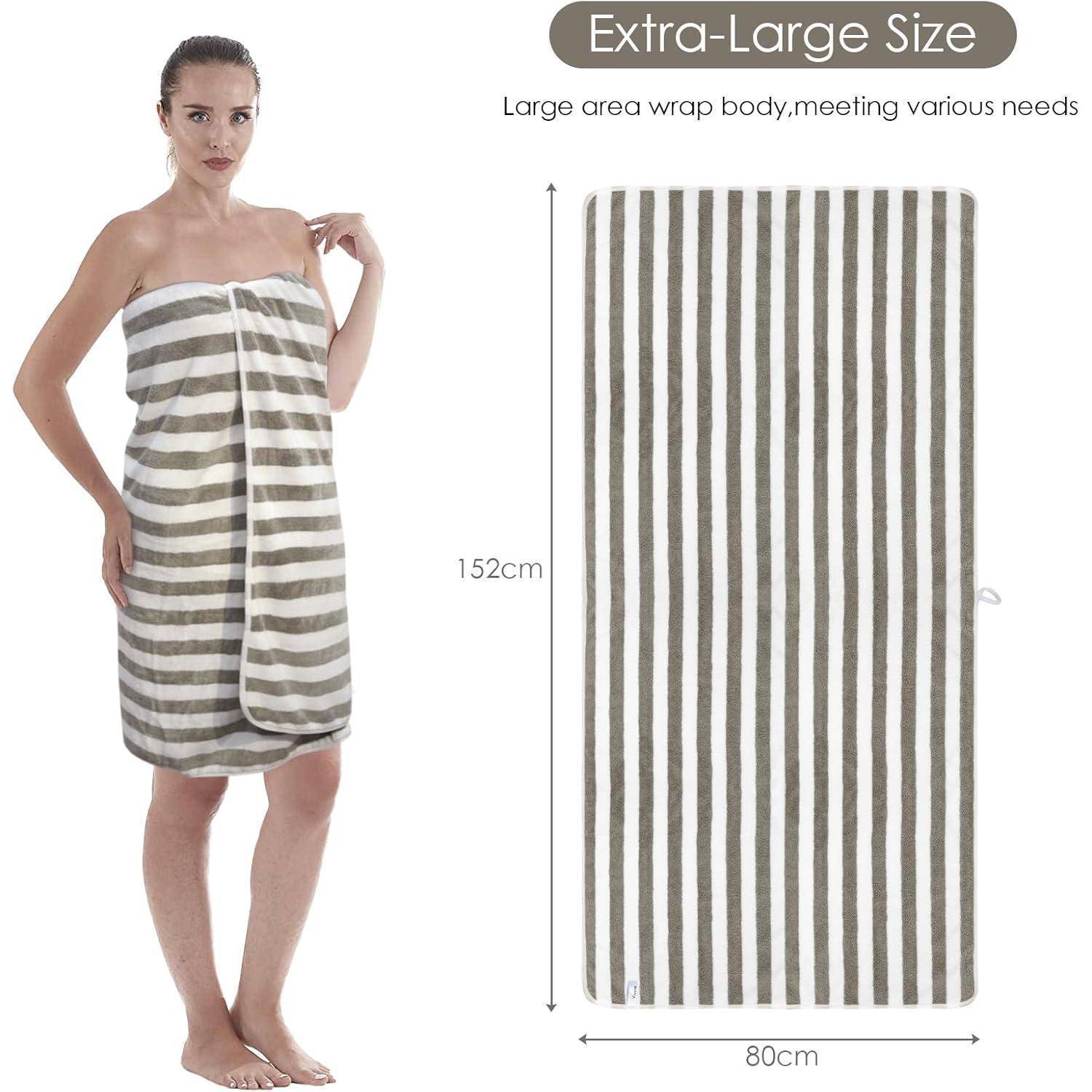 Frau in ein gestreiftes Handtuch gewickelt, steht neben demselben Handtuch ausgebreitet, wobei dessen Größe von 152 cm x 80 cm hervorgehoben wird.