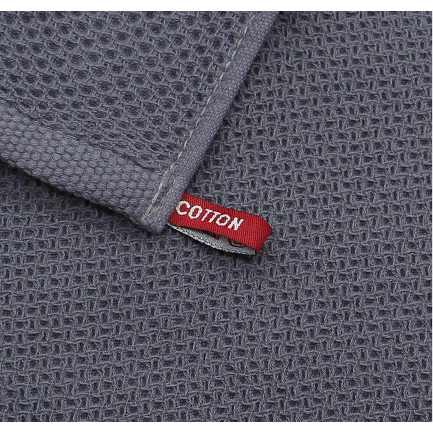 Eine Nahaufnahme eines grauen Stoffes mit Waffelmuster, versehen mit einem roten Etikett mit der Aufschrift ‚COTTON'.