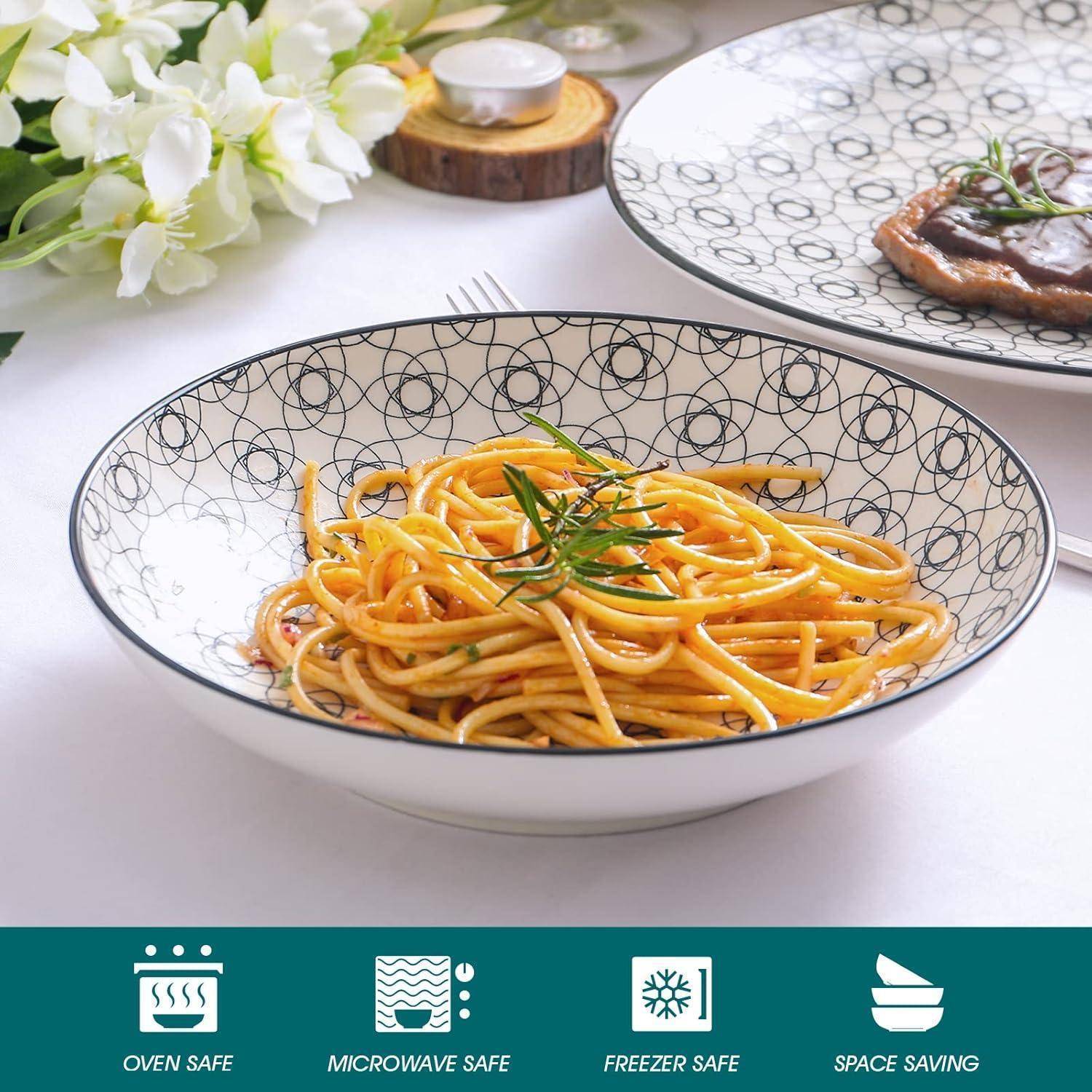 Eine Schüssel Spaghetti, garniert mit Kräutern, neben einem Steak-Teller. Symbole darunter zeigen, dass das Geschirr ofen-, mikrowellen- und gefrierschrankgeeignet ist, mit einem platzsparenden Design.