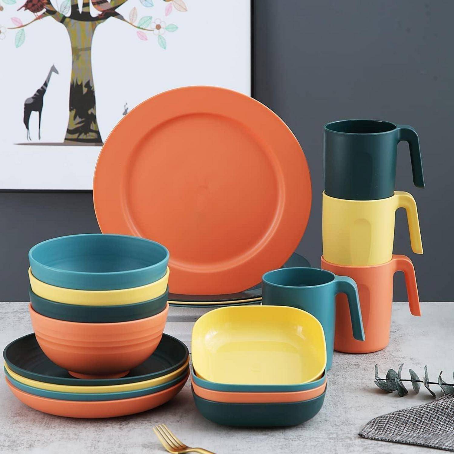 Farbenfrohes Geschirr-Set mit Tellern, Schüsseln und Tassen in Orange, Petrol und Gelb. Dekorative Baumkunst und Giraffenkunst im Hintergrund.