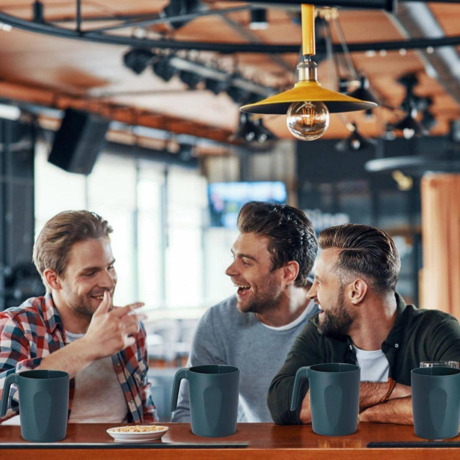 Drei Menschen lachen und unterhalten sich an einem Tisch in einem gemütlichen Café, mit Kaffeetassen vor sich und einer warmen, industriellen Atmosphäre.