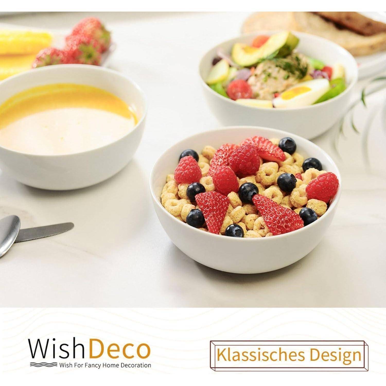 Ein Frühstückstisch mit einer Joghurtschüssel, die mit Himbeeren und Blaubeeren belegt ist, einem Obstsalat und einer Schüssel Suppe.