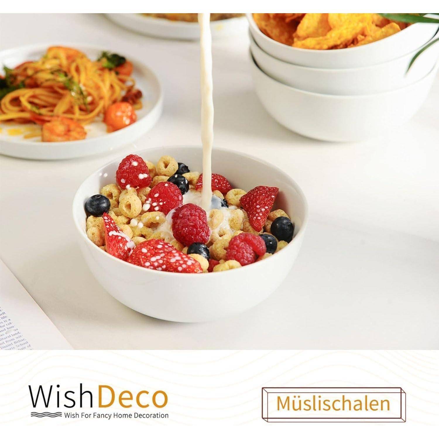 Schüssel mit Müsli, Milch, gemischten Beeren und Ringen, auf einem Tisch mit Tellern mit Essen im Hintergrund; Markierungstext lautet 