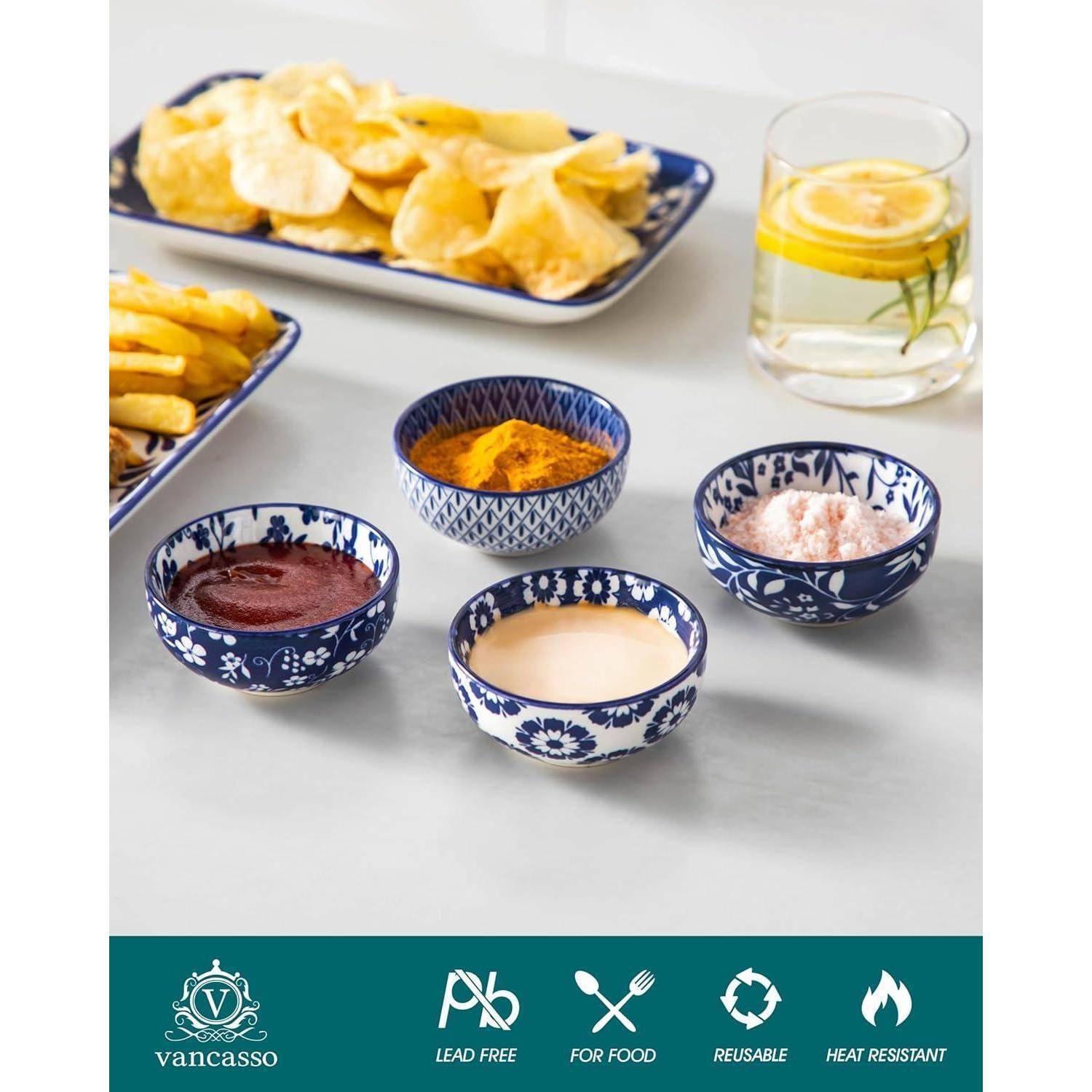Vier blau-weiß gemusterte Schüsseln auf einem Tisch, jede mit einer anderen Sauce oder Dip gefüllt, mit Kartoffelchips, Pommes und einem Zitronengetränk in der Nähe.