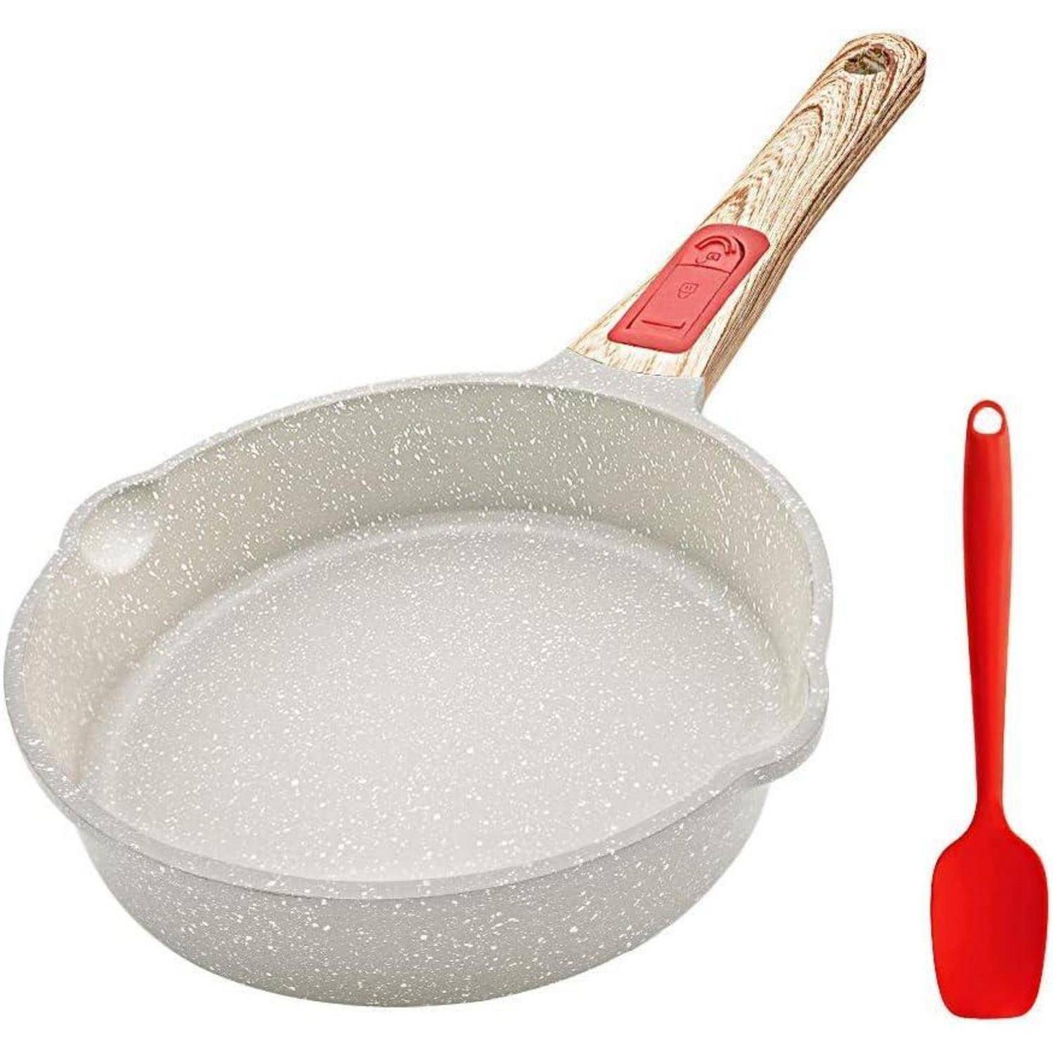 Weiße Antihaft-Pfanne mit einem Holzgriff neben einem roten Pfannenwender.