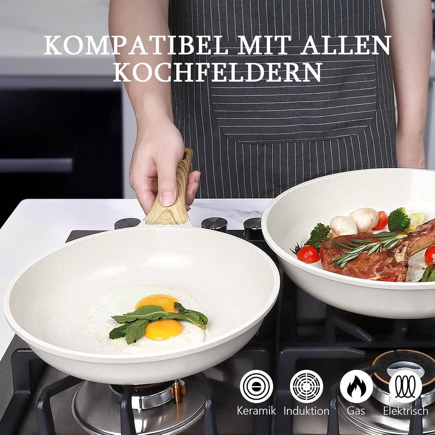 Ein Mensch hält eine Pfanne auf einem Herd mit Eiern in einer Pfanne und Gemüse in der anderen. Text lautet: 'KOMPATIBEL MIT ALLEN KOCHFELDERN'.