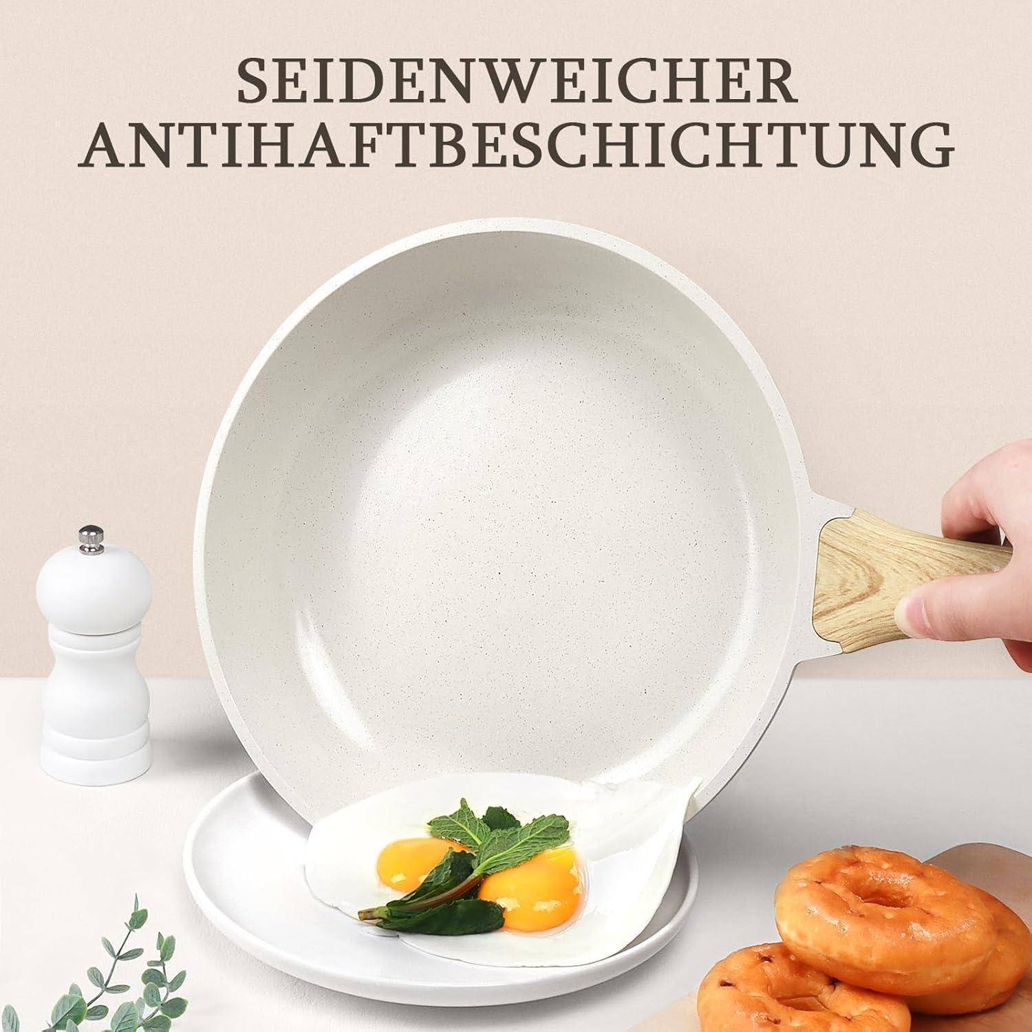 Eine Hand, die eine weiße Antihaft-Pfanne mit gebratenen Eiern neben Gewürzen, einer weißen Pfeffermühle und zwei Bagels auf einem hellen Hintergrund hält.