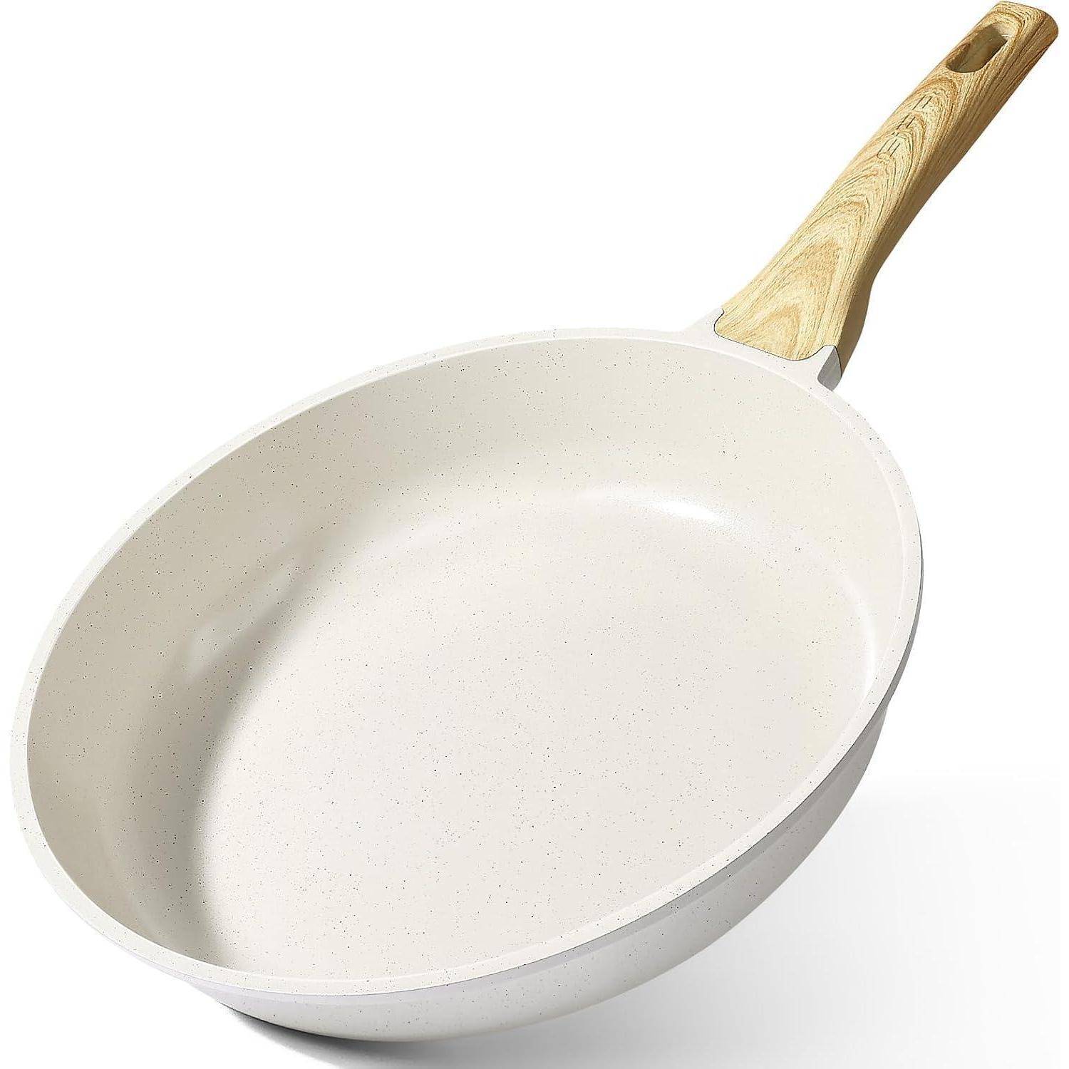 Eine weiße, antihaftbeschichtete Bratpfanne mit einem hellbraunen Holzgriff vor einem einfarbig weißen Hintergrund.