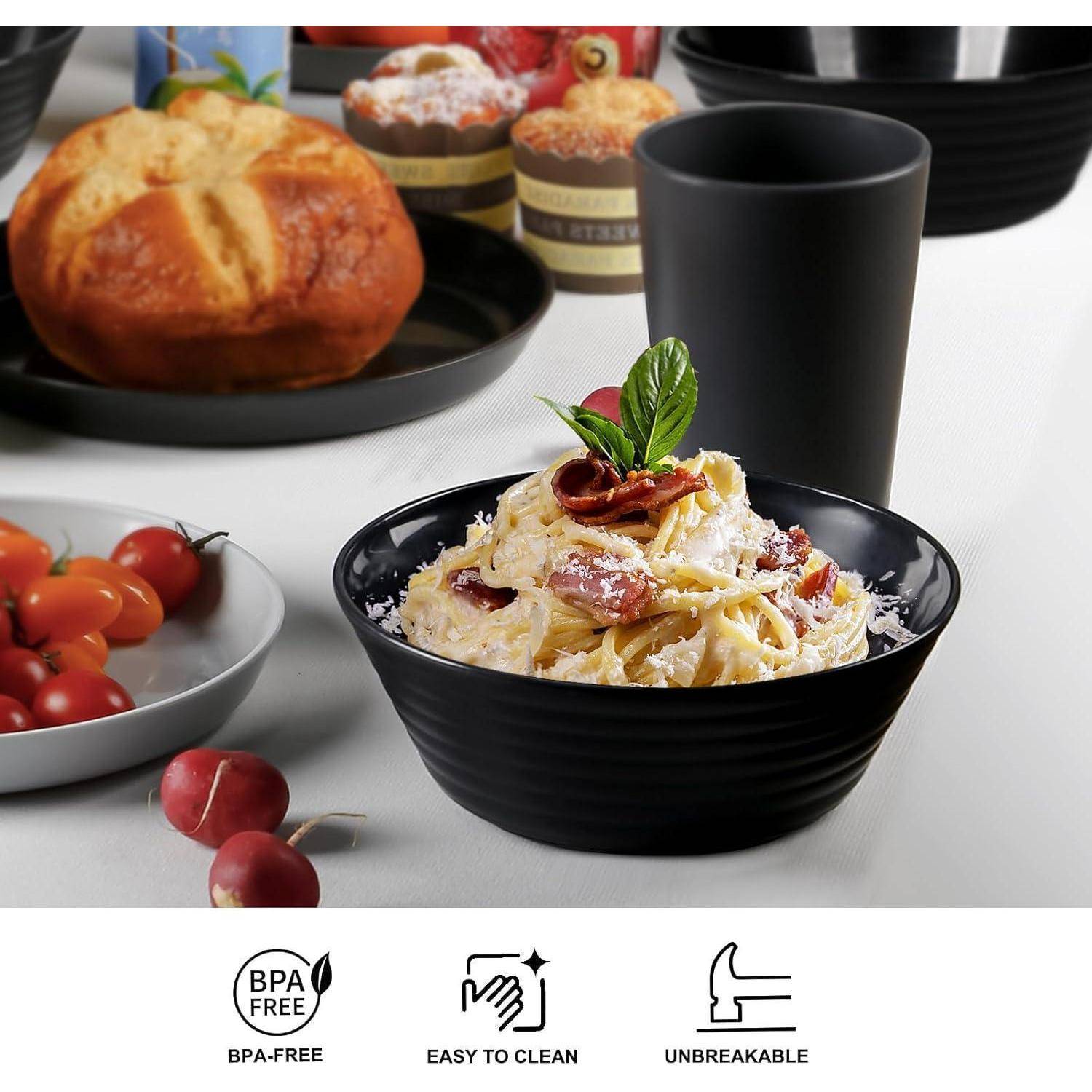 Pasta mit Käse und Speck belegt wird in einer schwarzen Schüssel serviert. Umgebende Gegenstände umfassen Brot, Tomaten und eine schwarze Tasse. Symbole weisen auf BPA-freie, leicht zu reinigende und unzerbrechliche Eigenschaften hin.