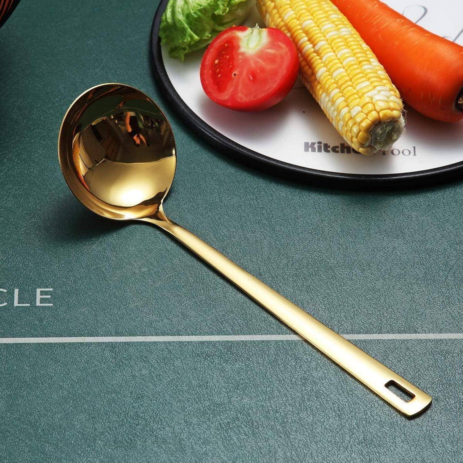 Ein goldener Löffel liegt auf einem grünen Tisch neben einem runden Teller, der eine Karotte, Mais, Tomate und Salat enthält.